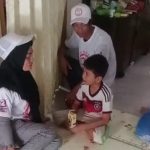 Para relawan bergerak sambil membagikan susu gratis kepada anak-anak dan warga.